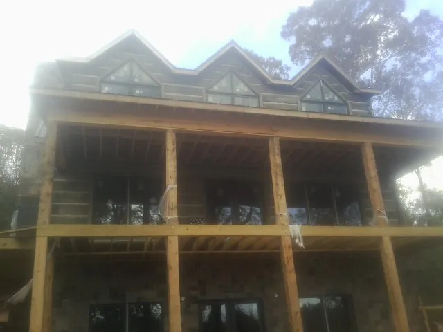 Dormers and porch framing on a large log home under construction — Roof Coating work by our crew in Lewisville