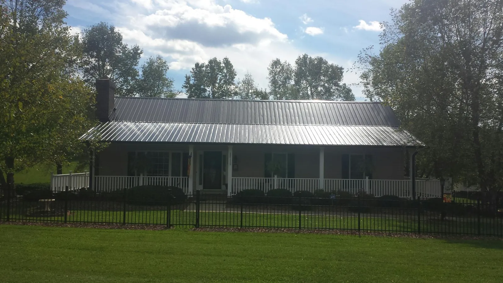 Gray metal roof on a brick ranch with a full width front porch — Gutter Guard Installation work by our crew in Lewisville