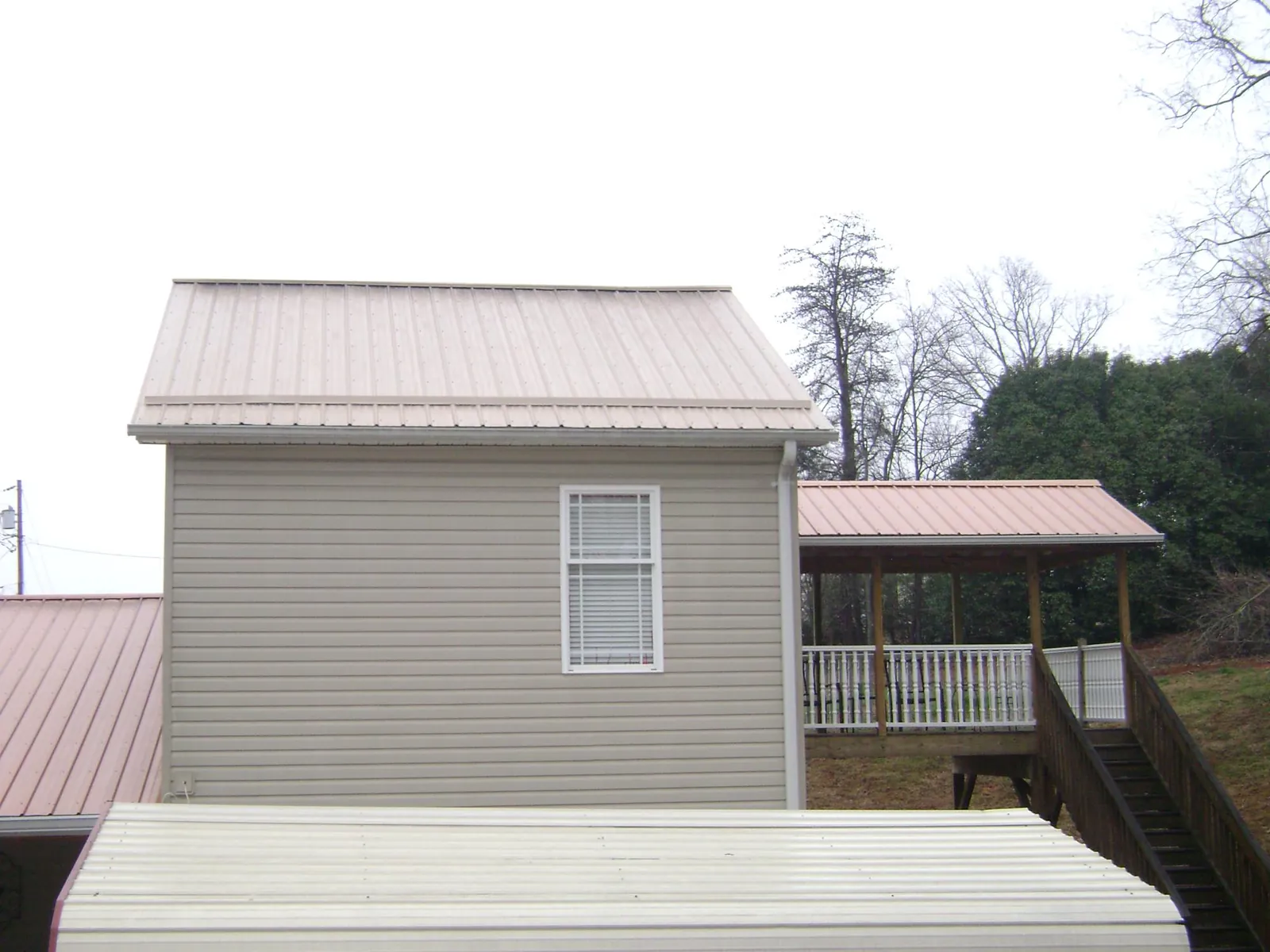 Tan metal roofs on a two story addition and attached porch, from a Roof Replacement job in Lewisville