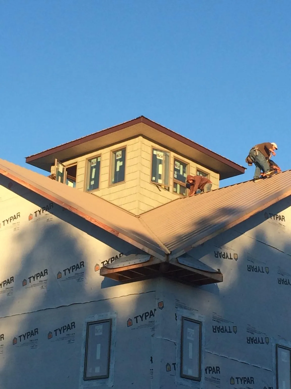 Roofers working around a rooftop cupola on a new metal roof at sunset — Roof Waterproofing in Lewisville by Roofing Brothers